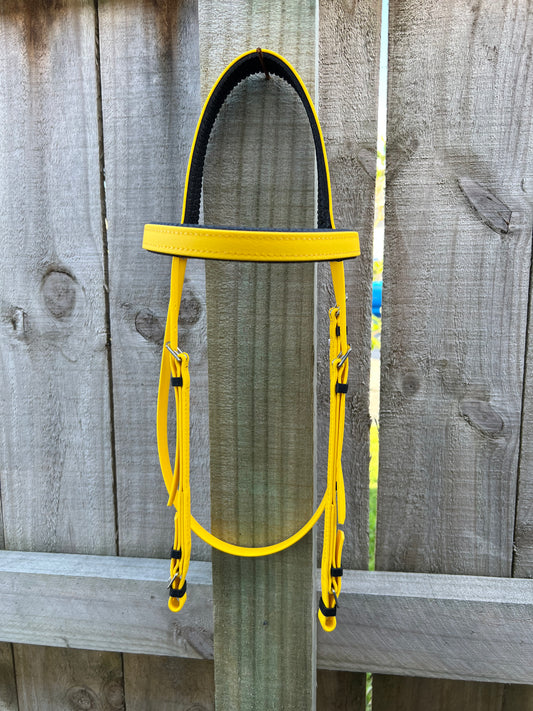 A Race Bridle - Yellow by LS Equestrian drapes over a wooden fence, its vibrant BioThane material standing out against the greyish-brown wood planks in the background.