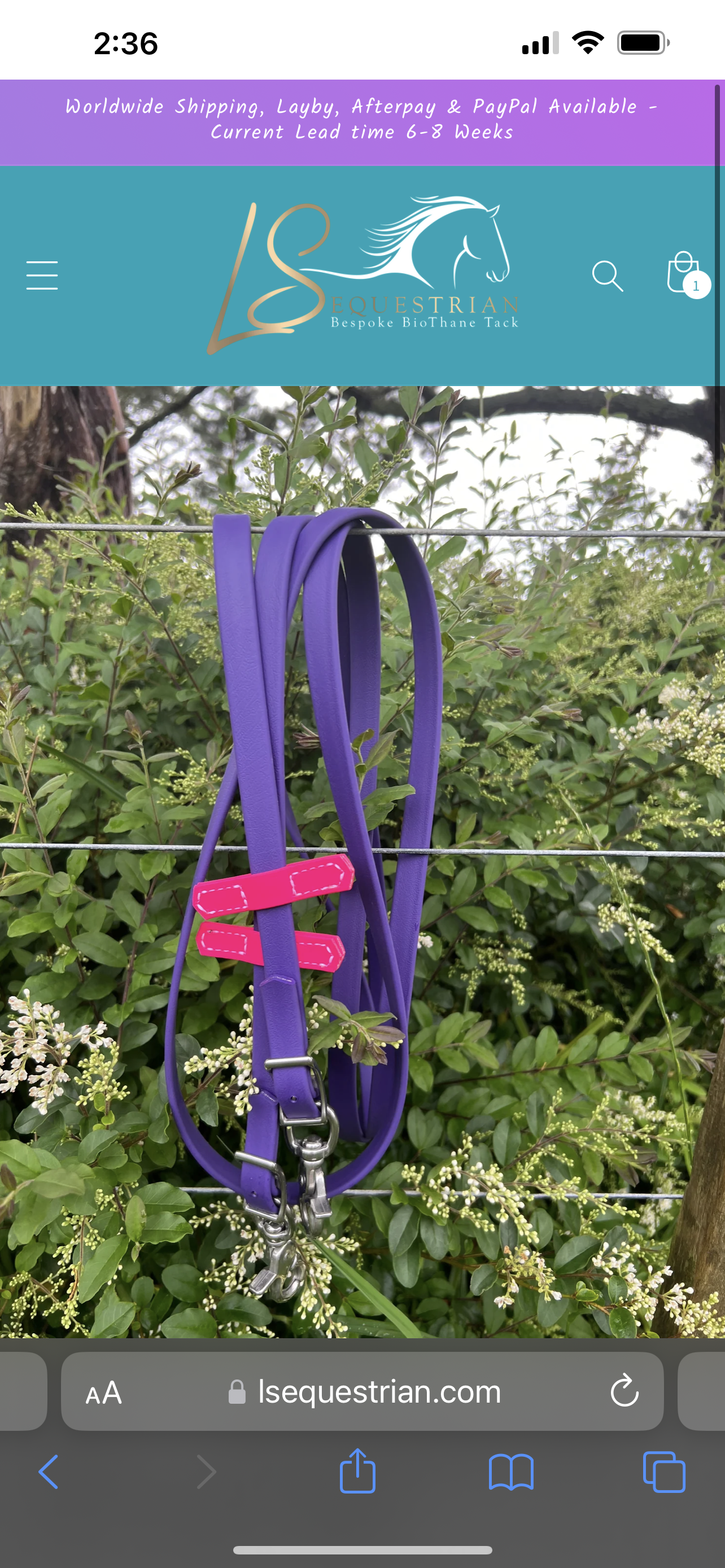 A customized Reins - Full BioThane in purple with pink accents, featuring stainless steel fittings, is displayed on a wire fence amidst lush greenery. The top banner of the image prominently displays the LS Equestrian logo and website details.