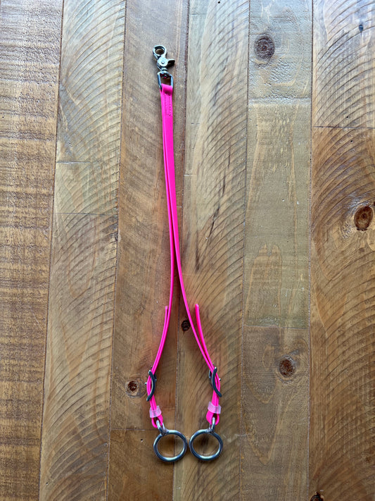 LS Equestrian's Breastplate Rings - Design Your Own is a pink leather splitter featuring a stainless steel clasp at the top and two metal rings at the bottom, displayed on a wooden surface.