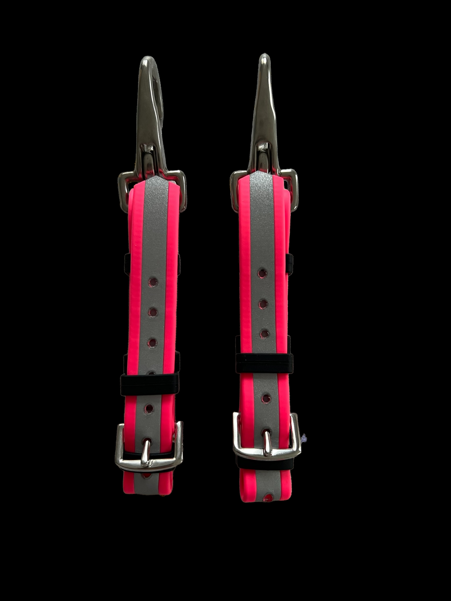 Two identical "CLEARANCE Bit Hangers - Reflective Pink" by LS Equestrian are displayed against a black background. These predominantly pink bit hangers, accented with gray, feature metal buckles and adjustment holes for size fitting. Crafted from durable BETA BioThane, they promise lasting resilience and a comfortable fit for your pet.