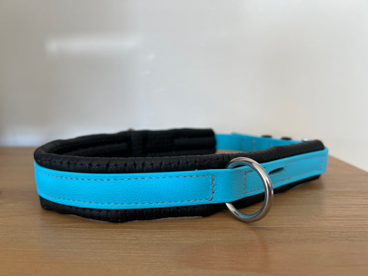 A close-up of a stylish blue and black Biothane®️ Bitless Nose Convertor from LS Equestrian, resting on a wooden surface. The convertor features a shiny metal ring for attaching a leash.