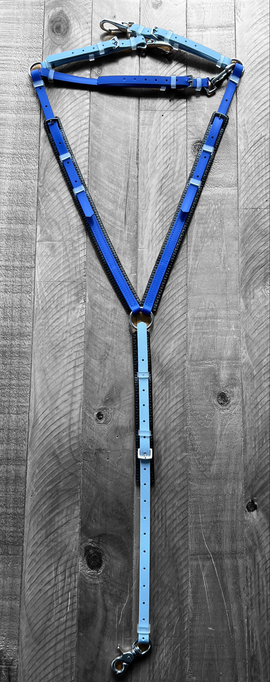 A custom-made Padded Breastplate in Pastel Blue and Royal Blue from LS Equestrian is laid out in a triangular shape on a wooden surface. The components, reminiscent of expert craftsmanship, are interconnected with metal rings and buckles, highlighting the brand's New Zealand design expertise.