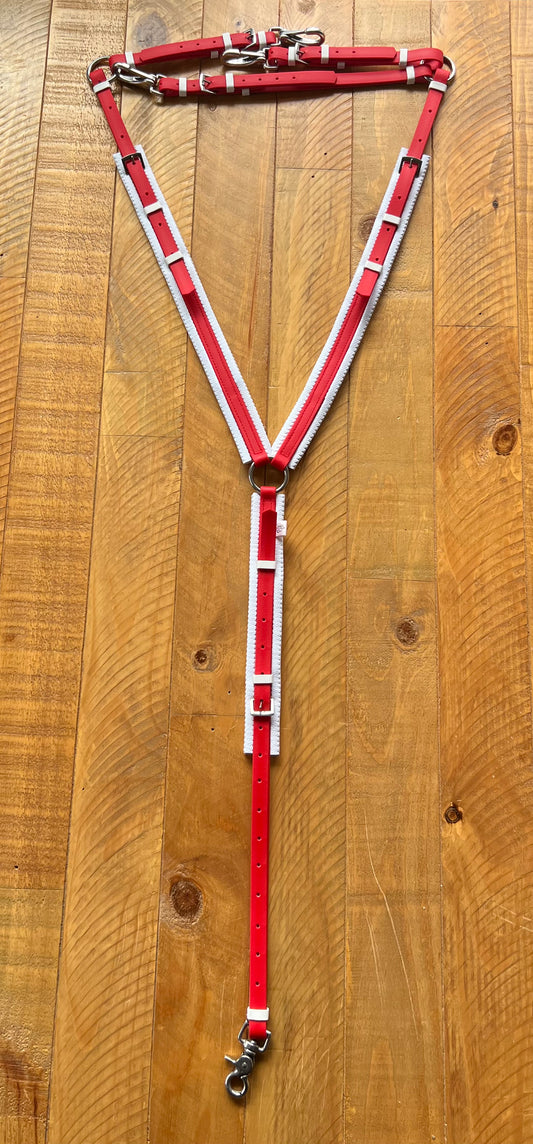 The Padded Breastplate in red and white from the LS Equestrian brand's range is custom-made with silver buckles and rings, displayed flat on a wooden surface.