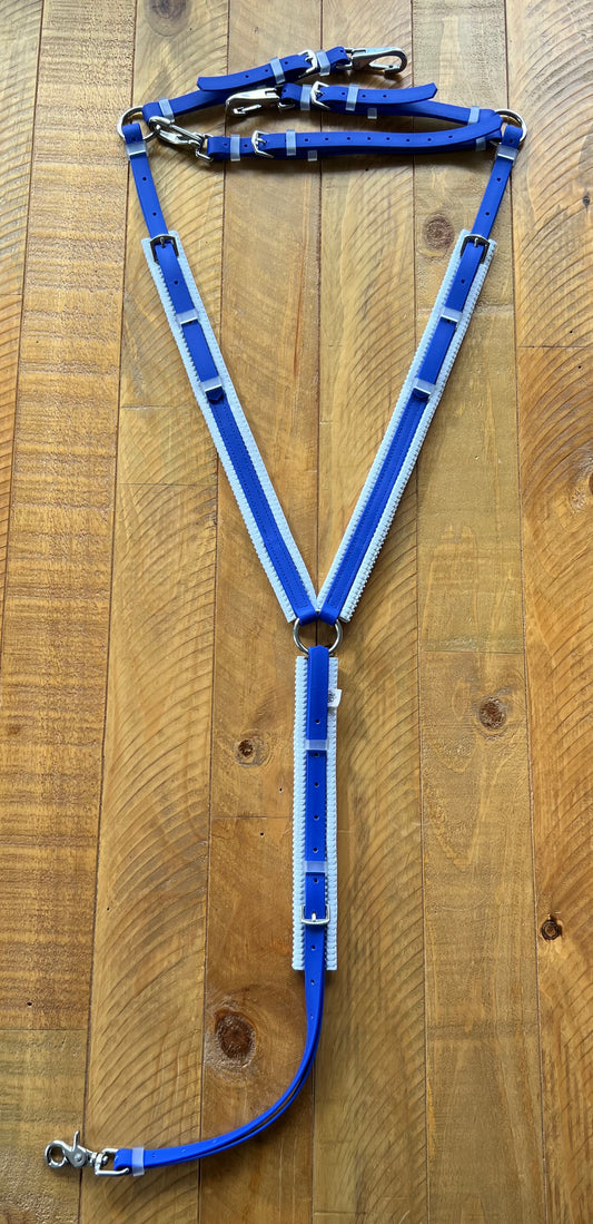 A custom-made horse harness in blue and white with stainless steel fittings and metal buckles is displayed on a wooden surface, complemented by the durable LS Equestrian Padded Breastplate in Royal Blue & White.