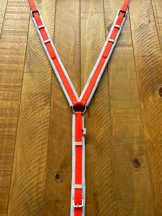 A Padded Breastplate from the LS Equestrian range, in Fluro Orange & White, crafted with BioThane material, is displayed on a wooden surface. The Y-shaped harness features adjustable buckles for a perfect fit.