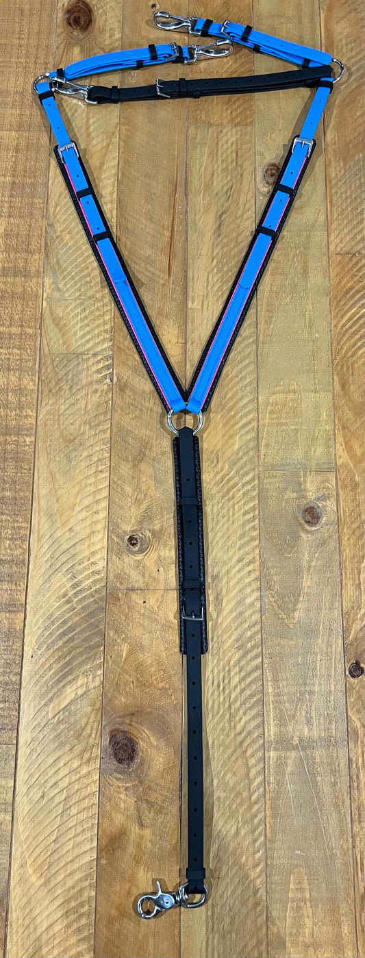 A custom-made cyan, hot pink, and black padded breastplate by LS Equestrian rests on a wooden surface. Equipped with adjustable straps and sturdy clips, this creation ensures both style and durability for pets.