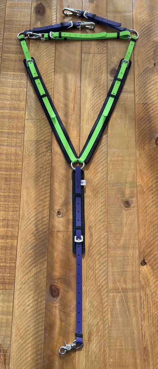 The LS Equestrian Padded Breastplate in Apple Green and Purple showcases vibrant BioThane straps elegantly arranged on a wooden surface. Expertly crafted with multiple buckles and metal clips, it's designed for both style and durability.